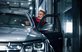 Stylish senior man with grey hair and mustache sitting into brand new modern car photo