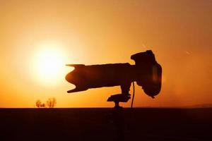 Side view of camera on tripod. Beautiful landscape with field illuminated by sunlight. In Moravia photo