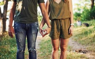 Making heart and love gesture by the hands. Young couple have a good time in the forest at daytime photo