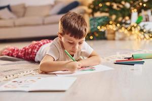 Little boy is in room with christmas tree is on the floor photo