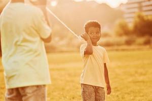 viejo teléfono de juguete. dos niños afroamericanos se divierten juntos en el campo durante el día de verano foto