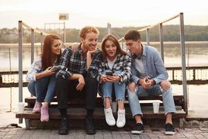 cerca del lago. grupo de jóvenes amigos alegres que están al aire libre divirtiéndose juntos foto