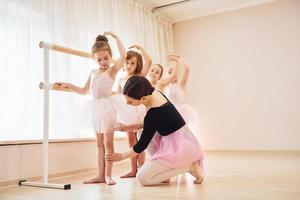 trabajando con el entrenador. pequeñas bailarinas preparándose para la actuación practicando movimientos de baile foto