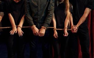 With rope in hands. Group of actors in dark colored clothes on rehearsal in the theater photo