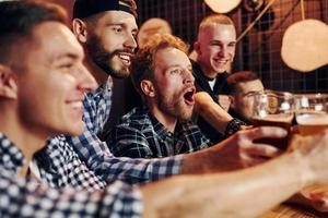 Fans cheer and shout. Group of people together indoors in the pub have fun at weekend time photo