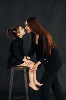 madre e hija están juntas en el estudio con fondo negro foto