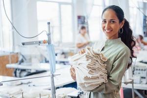 Woman dressmaker stands in the factory with cloth in hands photo