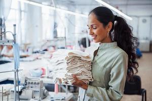 Woman dressmaker stands in the factory with cloth in hands photo