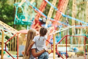 Embracing each other. Cheerful little girl her mother have a good time in the park together near attractions photo