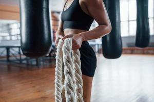 In black wear. Blonde sport woman have exercise with ropes in the gym. Strong female photo