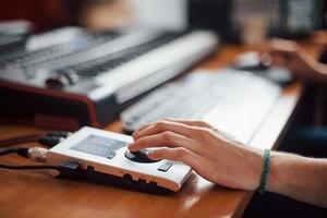 cierre la vista de la mano en la interfaz. ingeniero de sonido trabajando y mezclando música en interiores en el estudio foto