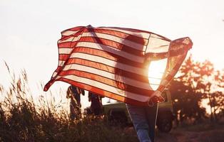 Girl in front of people. Friends have nice weekend outdoors near theirs green car with USA flag photo