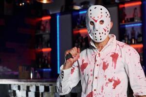 retrato de hombre con máscara de hockey que está en la fiesta temática de halloween con maquillaje y disfraces aterradores foto