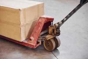 Close up view of dirty red pallet truck with paper box on it photo