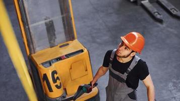 Young male worker in uniform is in the warehouse pushing pallet truck photo