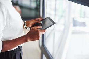 vista de partículas de una chica afroamericana que se encuentra en el interior de la oficina con una tableta en las manos foto