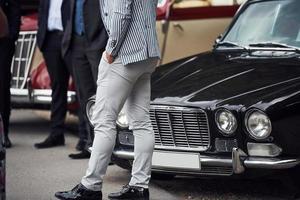 People in formal clothes standing near retro vehicles outdoors photo