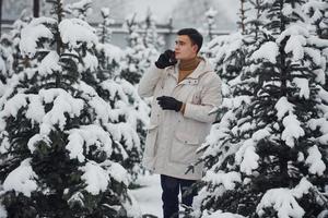 Man walking outdoors, talking by the phone and choosing christmas tree photo