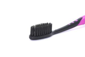 Charcoal toothbrush on a white background that cleans teeth with charcoal, designed for health-conscious people, environmentally friendly. photo