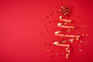 Christmas tree made from festive ribbon and confetti on a red background photo