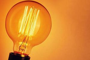 Vintage light bulb on yellow background, closeup. Glowing edison bulb photo