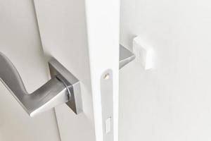 Silver door handle on a white door. Furniture accesories, interior element photo