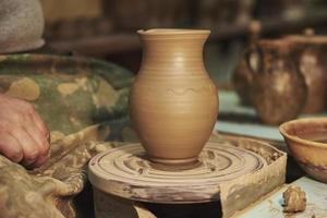 Clay pot on potter's wheel in workshop interior photo
