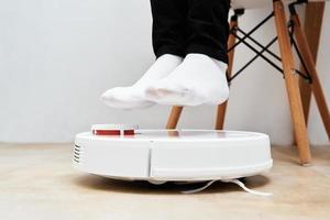 Robot vacuum cleaner working on floor with furniture photo