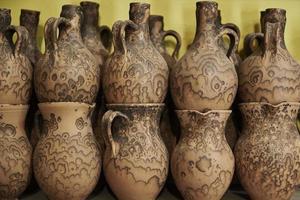 Many handmade clay jugs on shelf in workshop photo