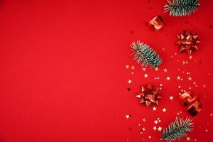 Fir branches, pine cones, dried fruits and festive confetti on a red background photo