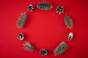 Wreath made of fir tree branches and festive pine cones on red background photo