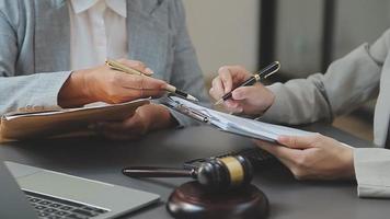 Business and lawyers discussing contract papers with brass scale on desk in office. Law, legal services, advice, justice and law concept picture with film grain effect video