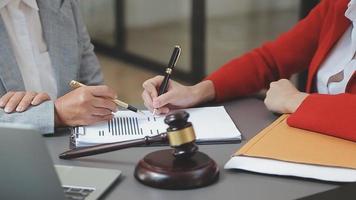 zaken en advocaten bespreken contractpapieren met koperen schaal op bureau in kantoor. wet, juridische diensten, advies, rechtvaardigheid en wet concept foto met film grain effect video