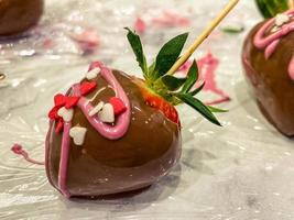 strawberries in chocolate. sweet dessert, appetizing berries in chocolate with multi-colored heart-shaped sprinkles and pink sauce. confectionery at home photo