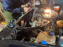 Working master locksmith repairman repairs a car under the hood in a workshop in a garage photo