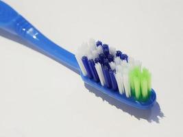 Isolated white photo of a plastic toothbrush that has been used several times. This toothbrush has a blue handle.