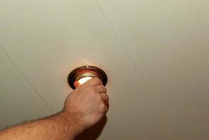 Installing a spot light, the hand inserts the lamp into the ceiling. Replacing a burned out incandescent bulb. photo