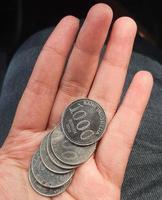 una mano sostiene varias monedas de rupias. estas monedas se suelen utilizar para dar a las manadas de personas que ayudan a cruzar el vehículo o les indican que den la vuelta. foto