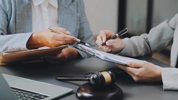 concept de justice et de droit. juge masculin dans une salle d'audience sur une table en bois et conseiller ou avocat masculin travaillant au bureau. concept de droit, de conseil et de justice juridique. video