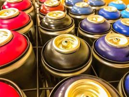 las latas de aerosol de pintura se exhiben detrás de una malla metálica. pulverizadores de pintura de varios colores. graffiti, pintura de autos. los globos están llenos de tintes multicolores para la creatividad foto