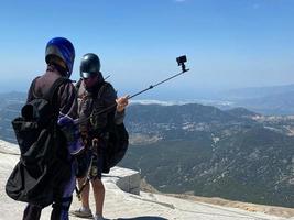 Two parachutists of an extreme tourist a client and an instructor are preparing for a parachute jump from a mountain photo