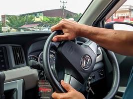 Pekanbaru, Indonesia - December 04, 2022 Male hand holding the steering wheel to drive a Daihatsu car photo