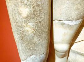 three-dimensional texture, stone and plaster sculpture, ancient art. on the texture of scuffs, chips, cracks and damage from time to time. man's legs with cracks photo
