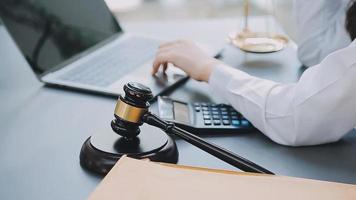 Justice and law concept.Male judge in a courtroom with the gavel, working with, computer and docking keyboard, eyeglasses, on table in morning light video