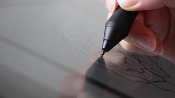 a mão de uma mulher segurando uma caneta stylus fazendo uma ilustração usando um tablet de artista de desenho digital. feche o tiro macro. video