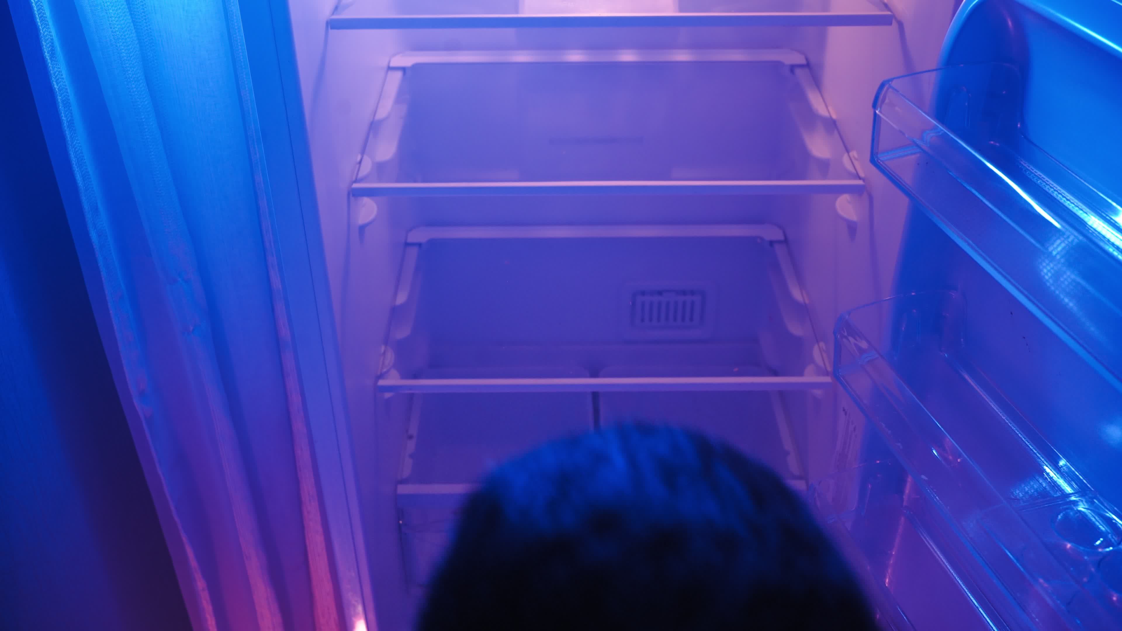 Man Opens the Empty Refrigerator at night in Neon Lighting. Poverty and