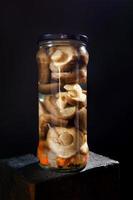 Pickled mushrooms with spices in a glass jar . Salted homemade mushrooms . Rustic food . photo