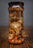 Pickled mushrooms in a glass jar . Salted homemade mushrooms . Rustic food . photo