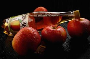 KRASNOYARSK, RUSSIA - JUNE 09, 2022 A lying bottle of Bon Season apple cider in drops of water and red apples. photo