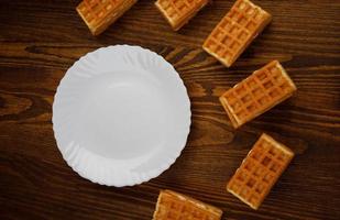 Viennese ruddy waffles lie around an empty white plate. photo